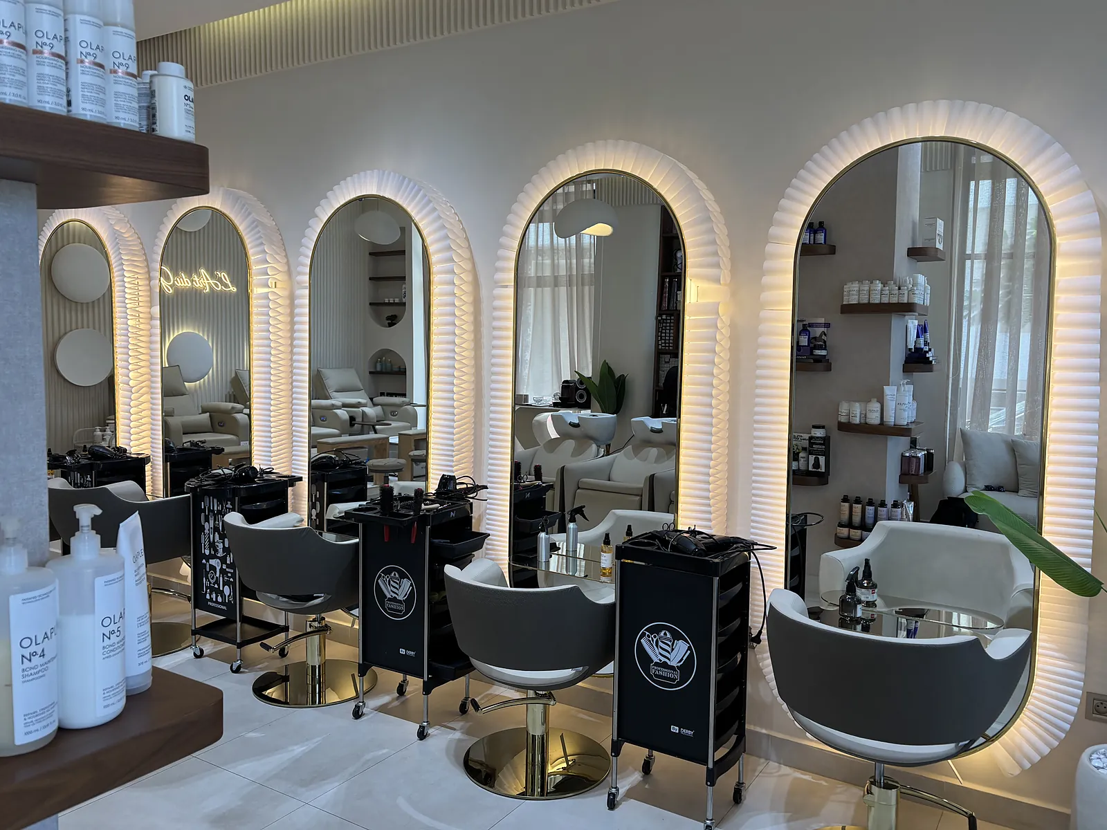 Les grands miroirs en arche rétroéclairés du salon, devant les fauteuils de coiffure