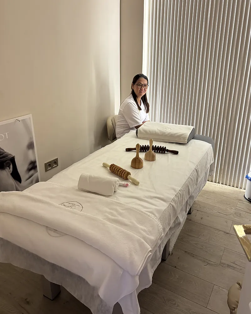 La salle de massage : une praticienne du salon derrière la table, avec les rouleaux et les ventouses en bois de madérothérapie