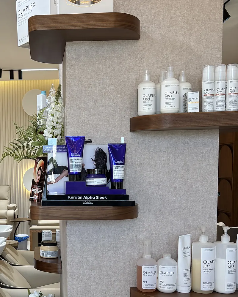 Les étagères en bois du salon avec les soins Olaplex et L'Oréal Professionnel